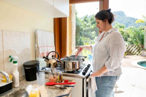 Person stirring food in a pot on the stove.