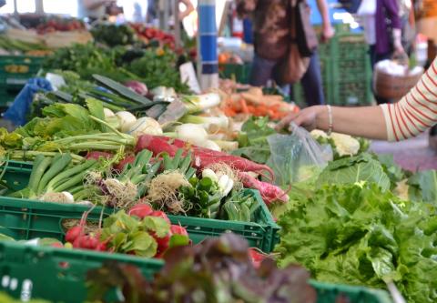 shopper selecting from bins of fresh produce on a table at a market