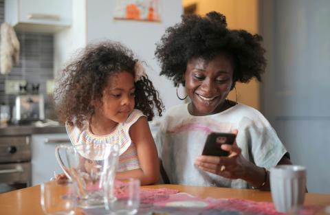 mother and daughter sitting at the kitchen table scrolling through nutrition information on the phone