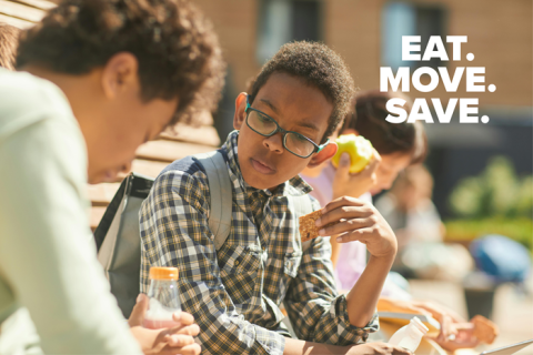 Children sitting on a bench outside eating after school snacks.