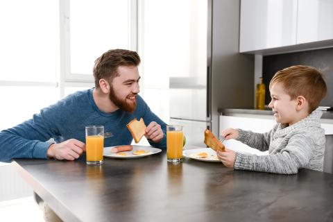 Image of joyful father bonding with son in kitchen