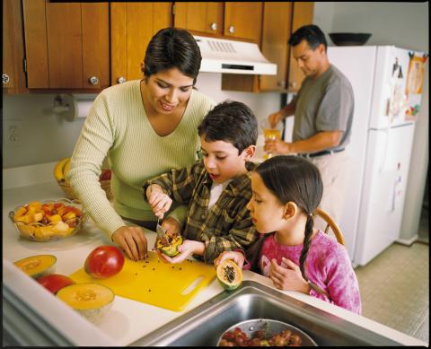 children help mother prepare fruit in the kitchen