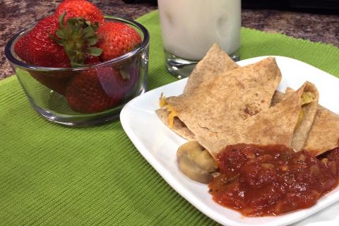 mushroom and cheese quesadilla with salsa, bowl of strawberries and glass of milk