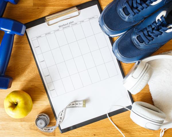 clipboard with a workout plan alongside exercise equipment