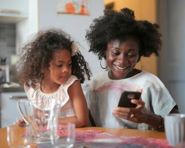 mother and daughter sitting at the kitchen table scrolling through nutrition information on the phone