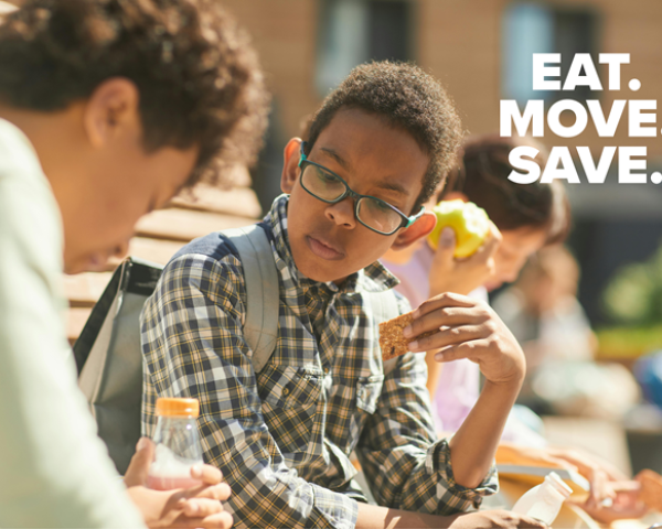Children sitting on a bench outside eating after school snacks.
