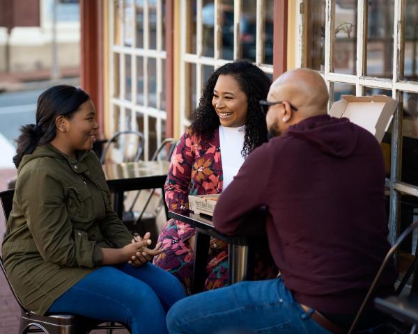 family enjoying a pizza at a table outdoors
