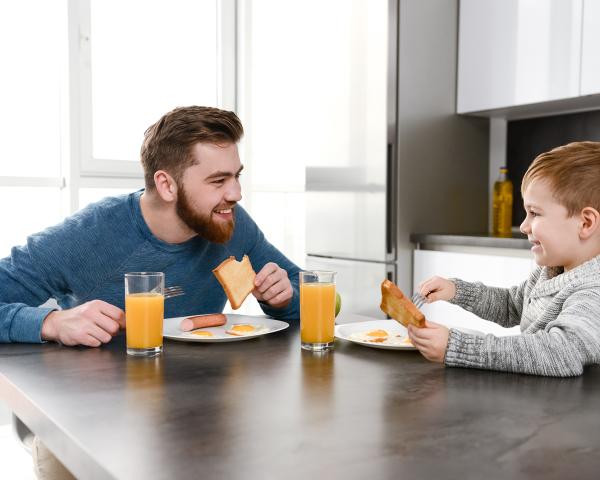 Image of joyful father bonding with son in kitchen