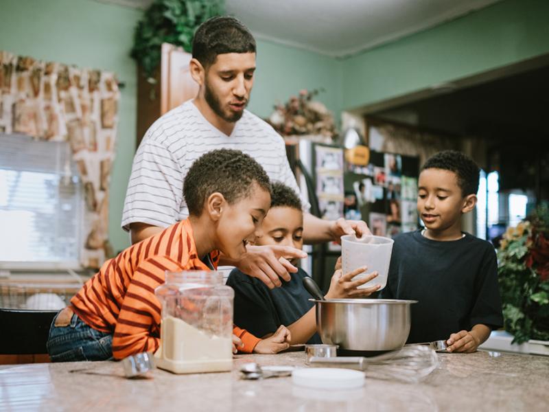 3 boys and father measuring ingredients into a bowl