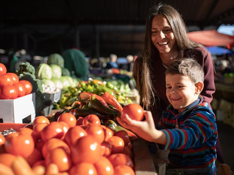 Mother and son pick out tomatoes at a farmers market