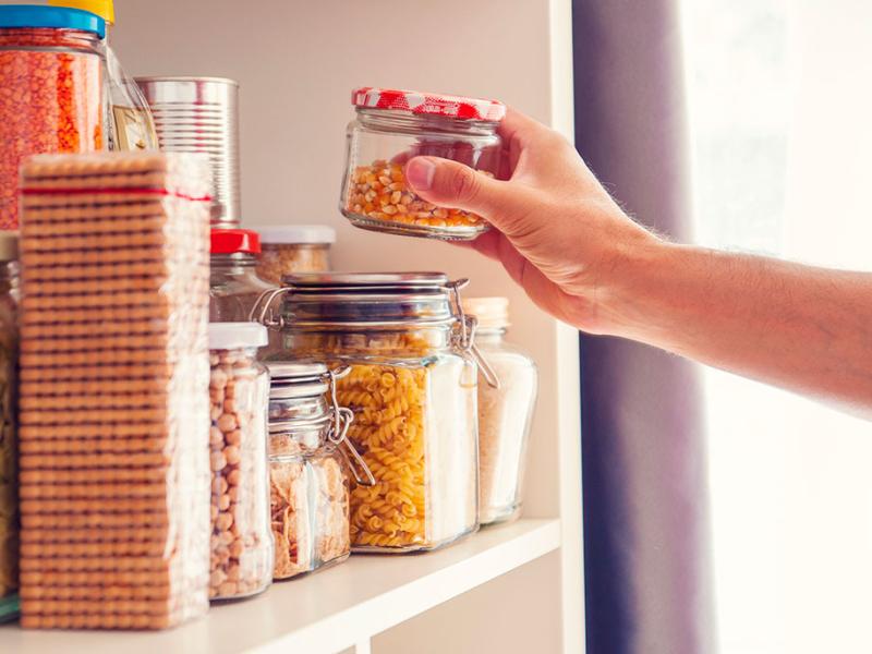 man reaching into pantry for a jar of dried corn