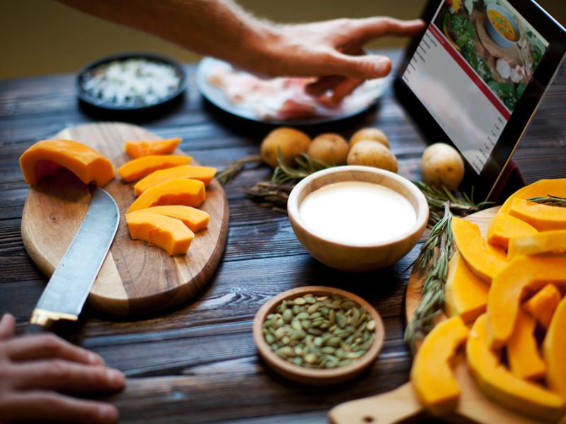 cutting squash and following recipe on a tablet