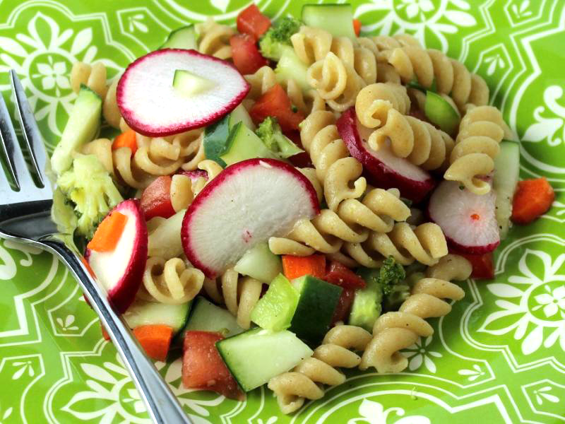 pasta salad with vegetables on a green and white plate