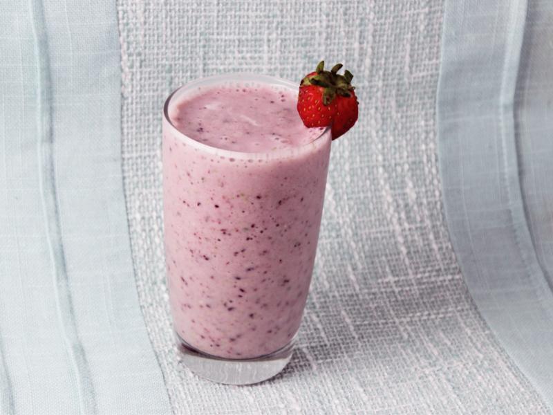 pink smoothie in a cup with strawberry garnish