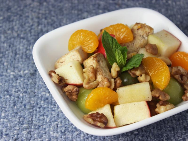 dish of tofu, fruit salad, and walnuts topped with sprig of mint