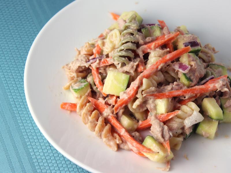 plate of tri-colored cooked rotini pasta mixed with tuna, carrots, and other vegetables