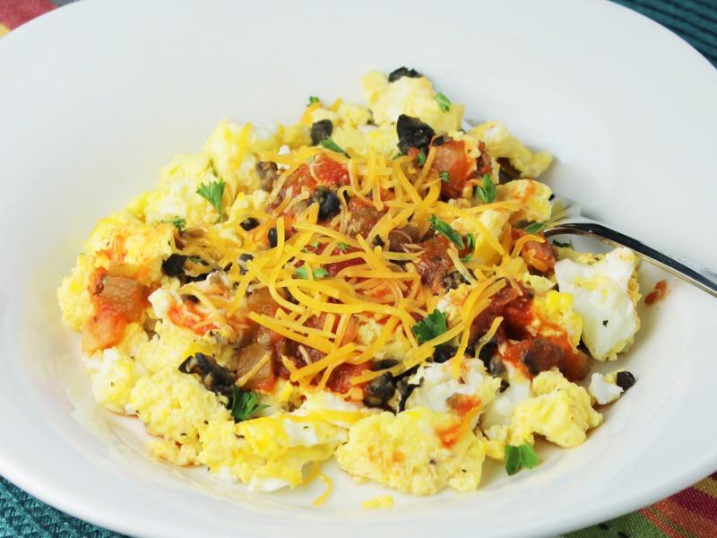 scrambled eggs with olives, green onion, salsa, cheese