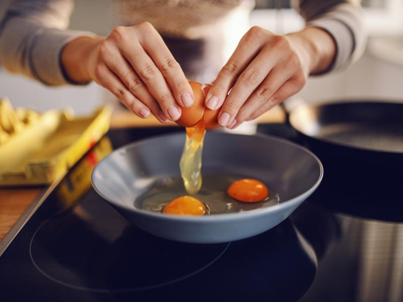 Person cracking eggs into a pan