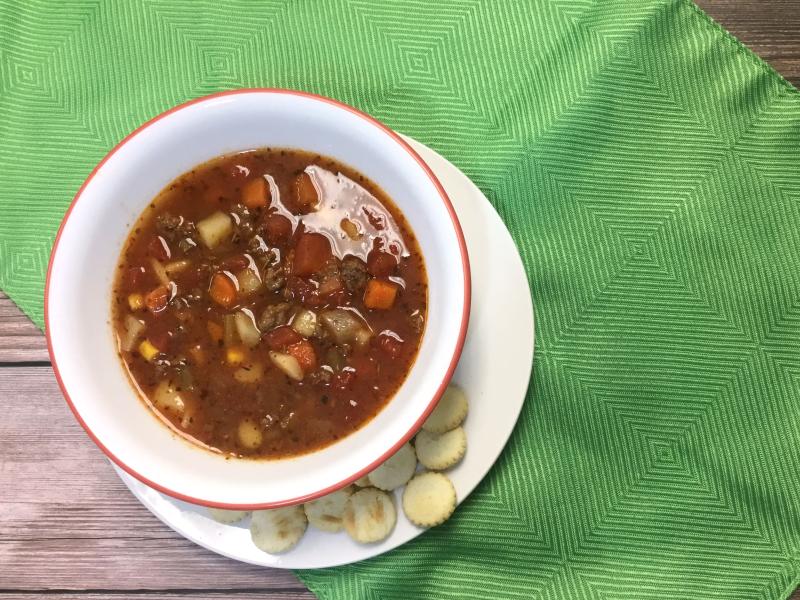 bowl of venison vegetable soup with oyster crackers on the side