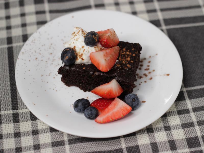 rectangle of chocolate cake topped with berries and whipped cream