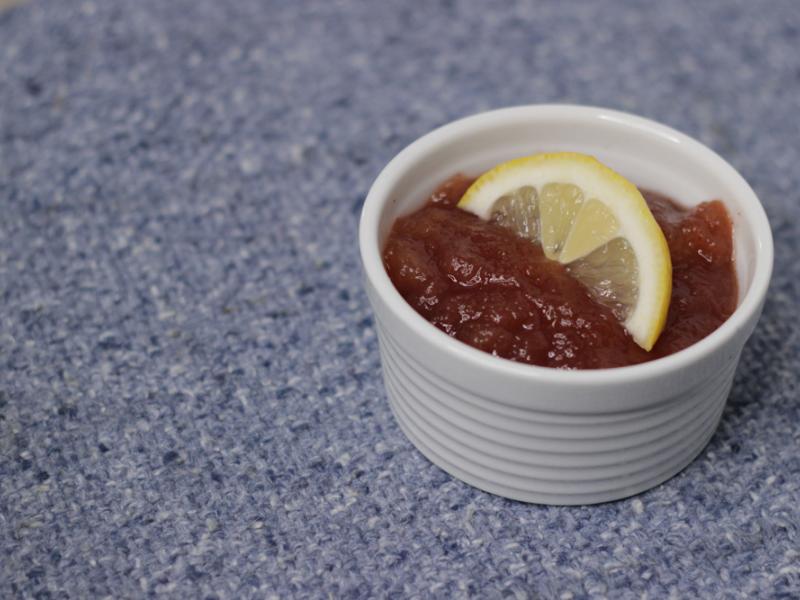 Dish of cranberry applesauce with lemon garnish.