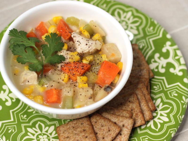 Bowl of prepared chicken corn chowder recipe with a side of wheat crackers.