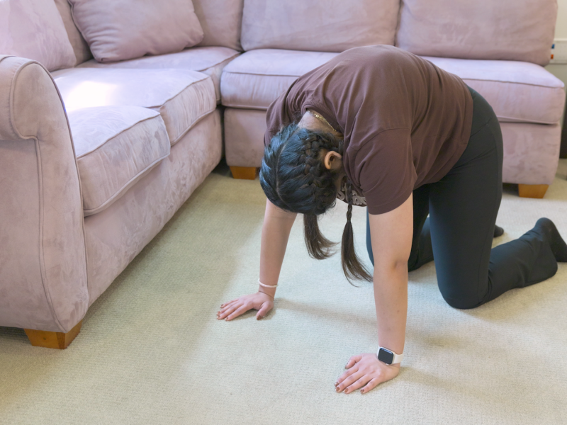 woman on the floor doing cat-camel stretch