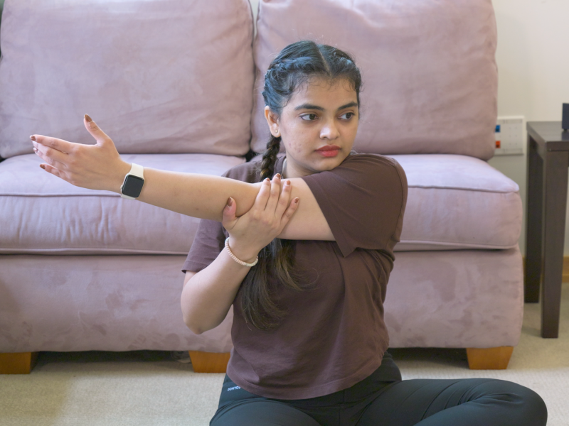 woman sitting on the floor doing shoulder stretch