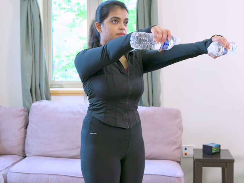 woman doing Front Arm Raises with water bottles as weights