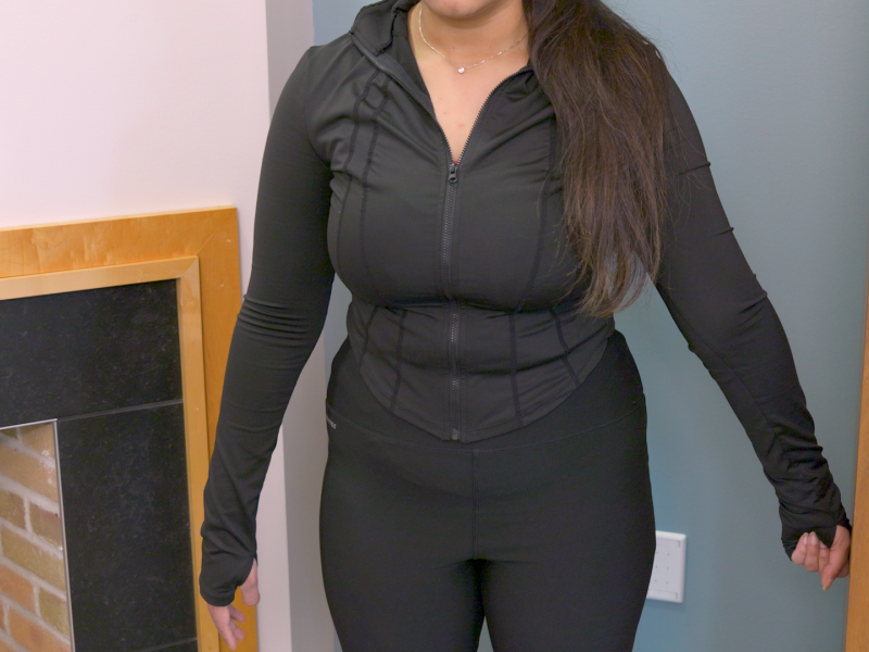 Woman standing with back to the wall and arms slightly out at her side