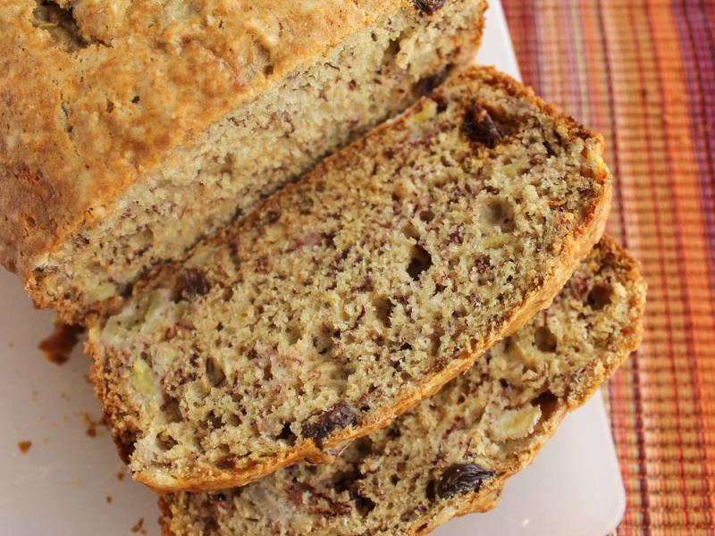 loaf of Banana Wheat Quick Bread with two pieces sliced on a cutting board