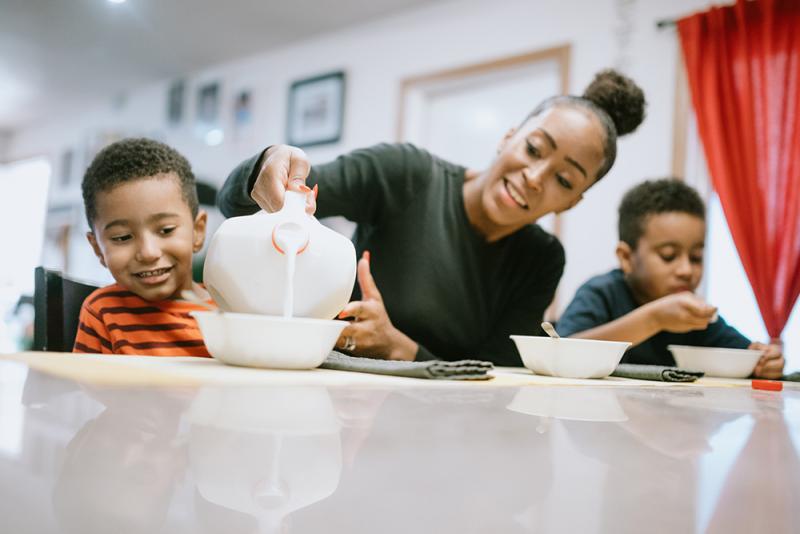 mom pouring milk into son's cereal bowl