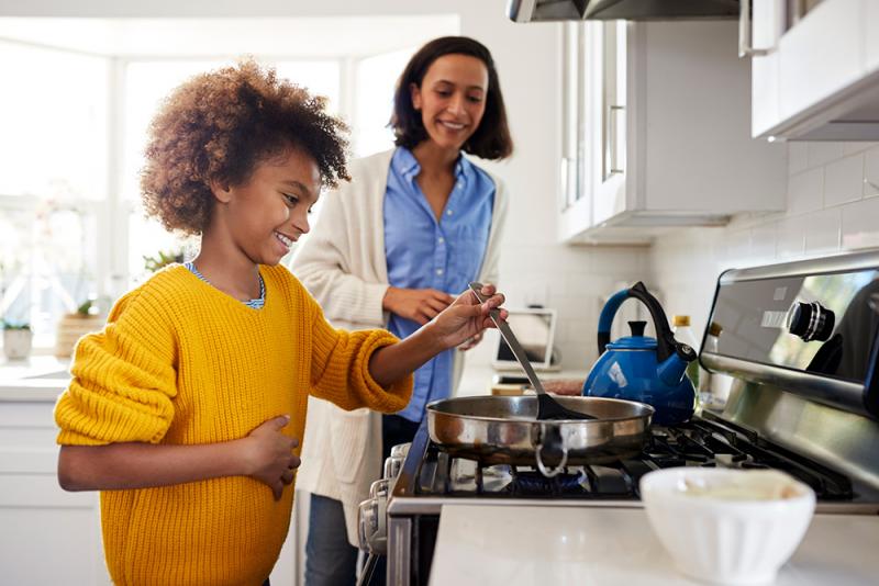 child stirring skillet on stove top