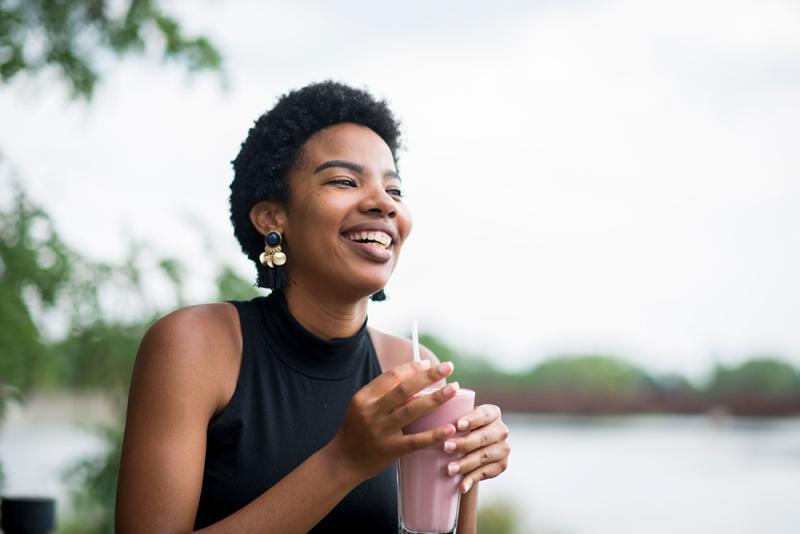 woman drinking smoothie by lake