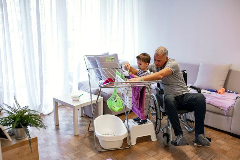 dad and toddler son hang laundry to dry