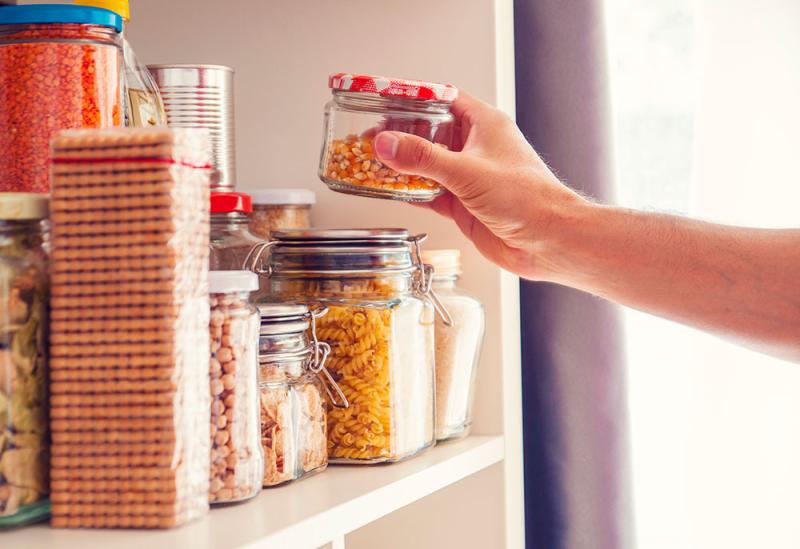 man reaching into pantry for a jar of dried corn