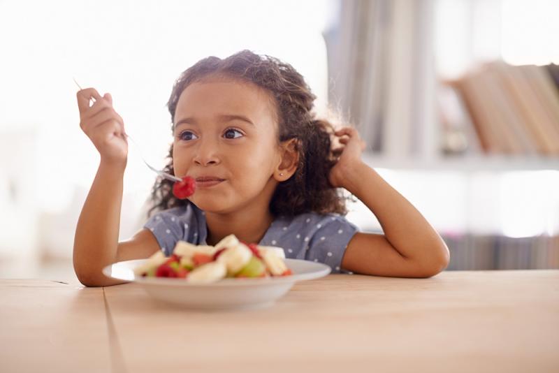 little girl eating fruit with a fork