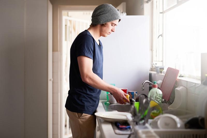 man washing dishes at sink