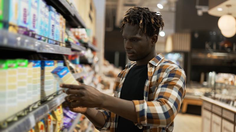 A man compares food labels of snack foods while shopping at the store.